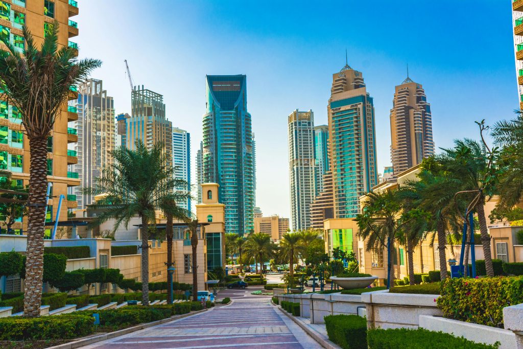 A vibrant view of Dubai's iconic skyscrapers and palm trees against a blue sky in daylight.